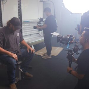 Behind-the-scenes of a video production session with crew and equipment in a modern studio setting.